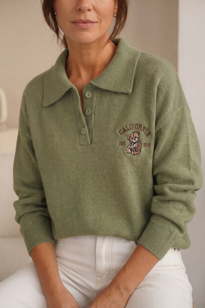 Mujer vistiendo jersey de punto verde oliva con cuello polo y bordado de oso.