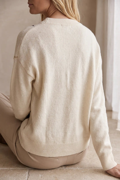 Vista trasera de mujer con jersey beige de punto de CHICA del Sur y pantalones beige.
