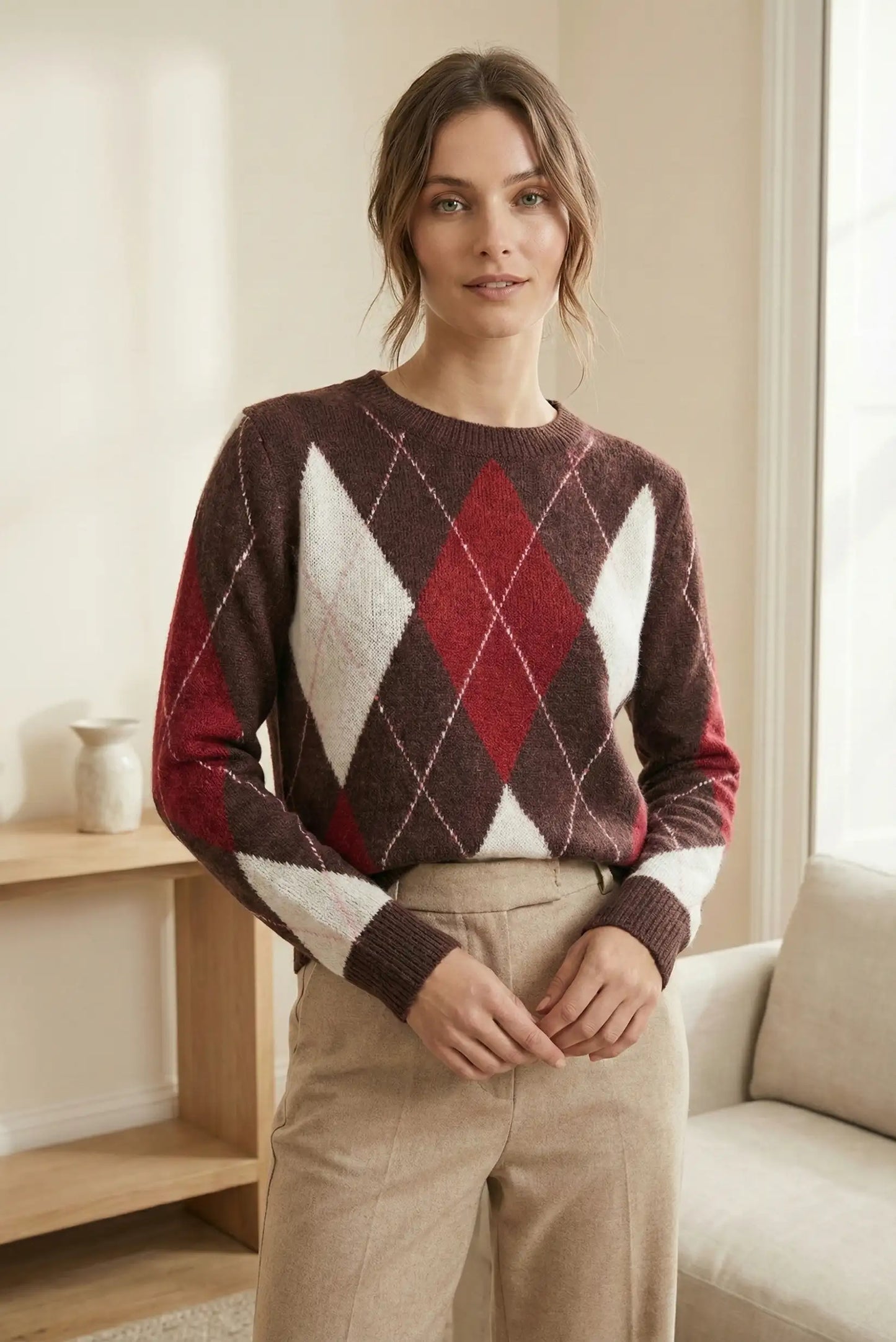 Mujer con jersey de rombos marrón, rojo y blanco, pantalones beige, en ambiente interior