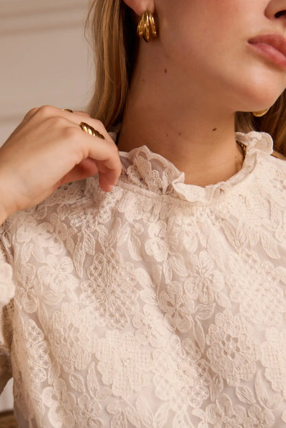 Blusa de encaje floral con cuello fruncido y detalles delicados, ideal para looks femeninos y elegantes.