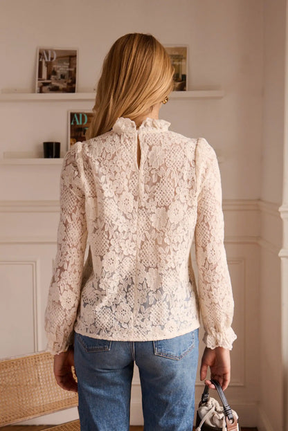 Blusa de encaje floral con mangas acampanadas y detalles en la espalda, combinada con jeans
