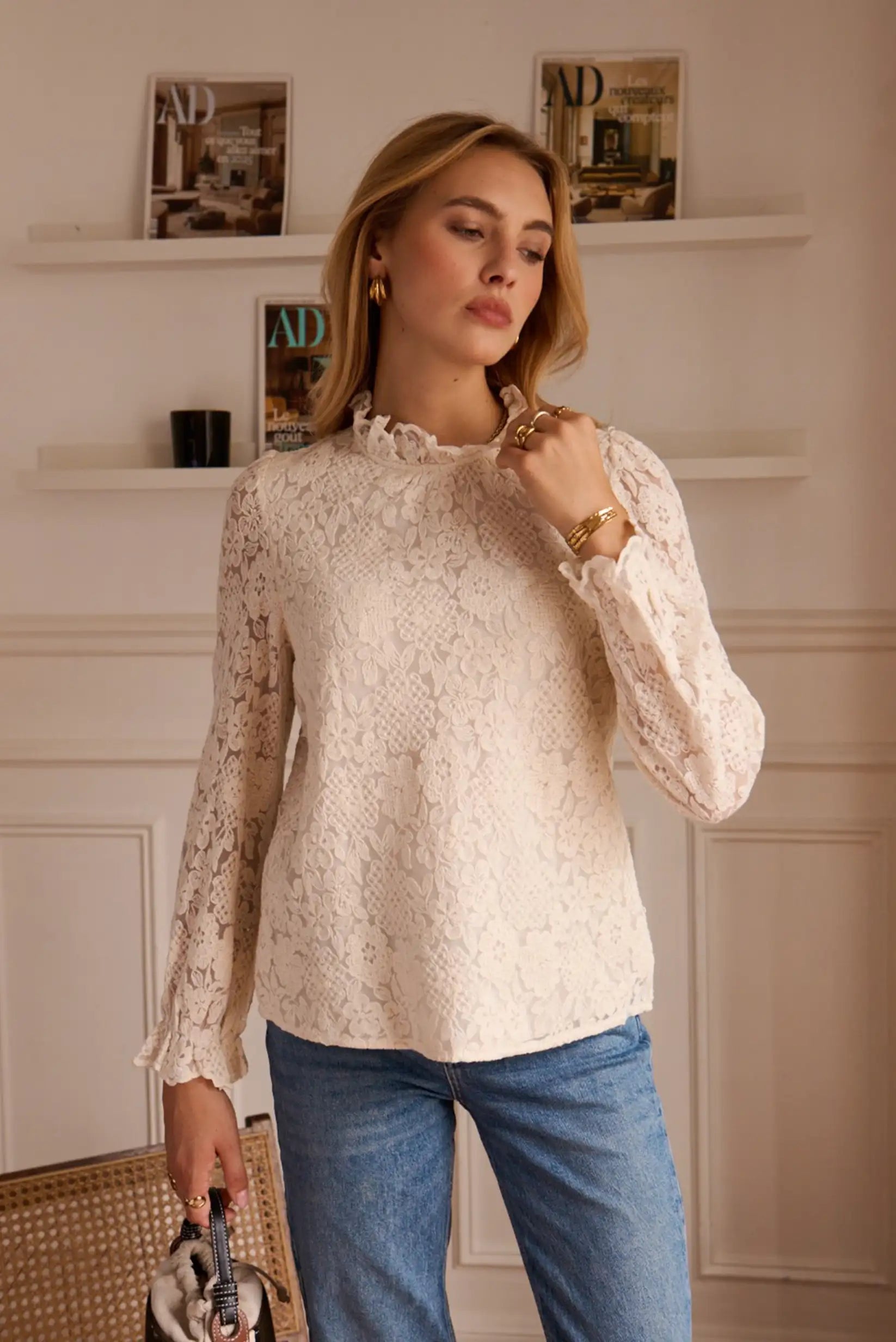 Blusa de encaje blanco con mangas largas y cuello redondo, combinada con jeans azules para look casual elegante