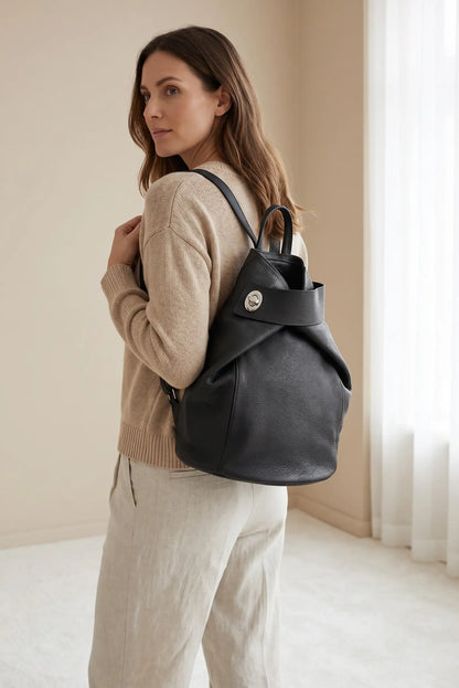 Mujer con mochila grande de cuero negra, estilo urbano, en ambiente minimalista