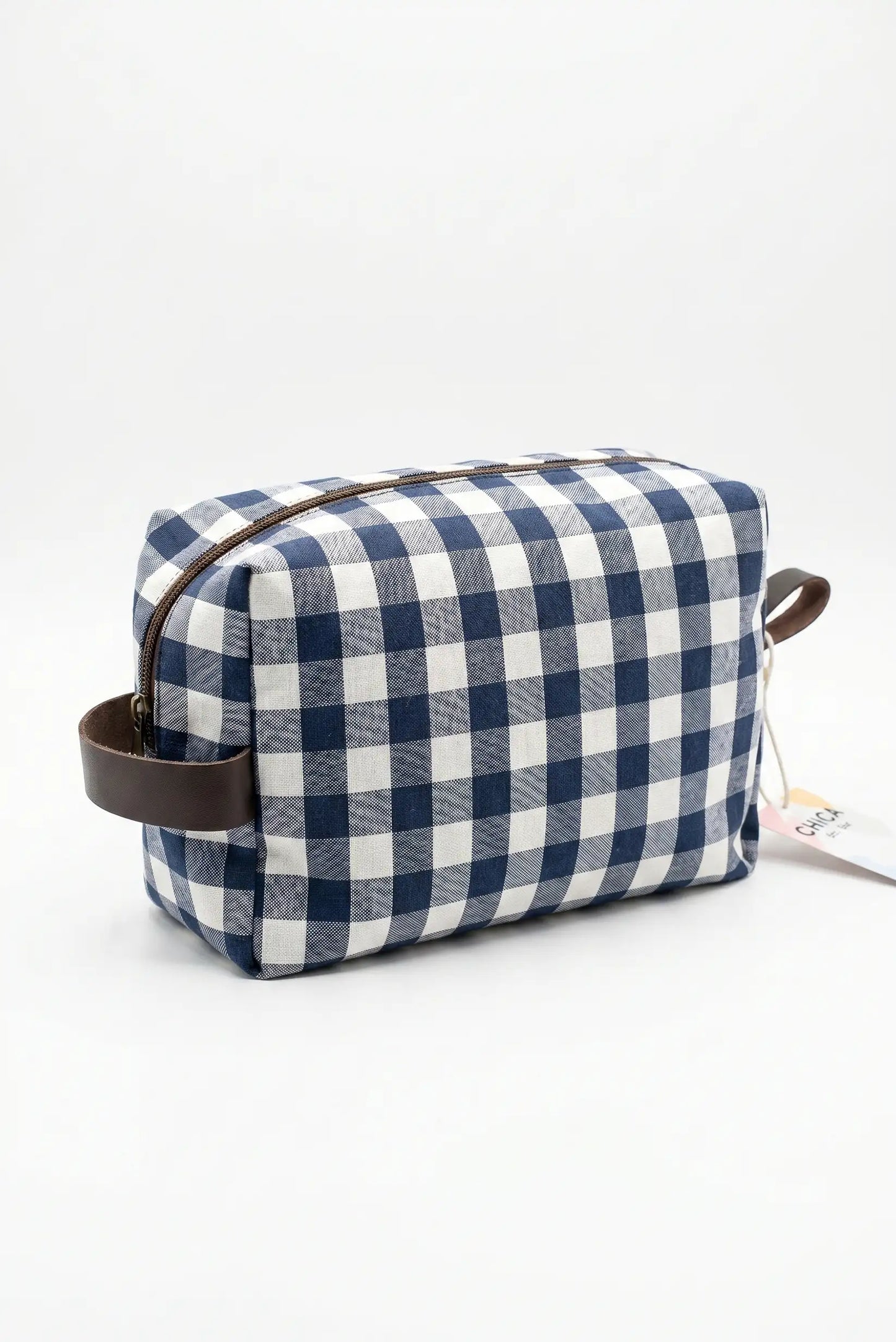 Neceser de tela cuadros vichy azul y blanco con asas marrones y cremallera.