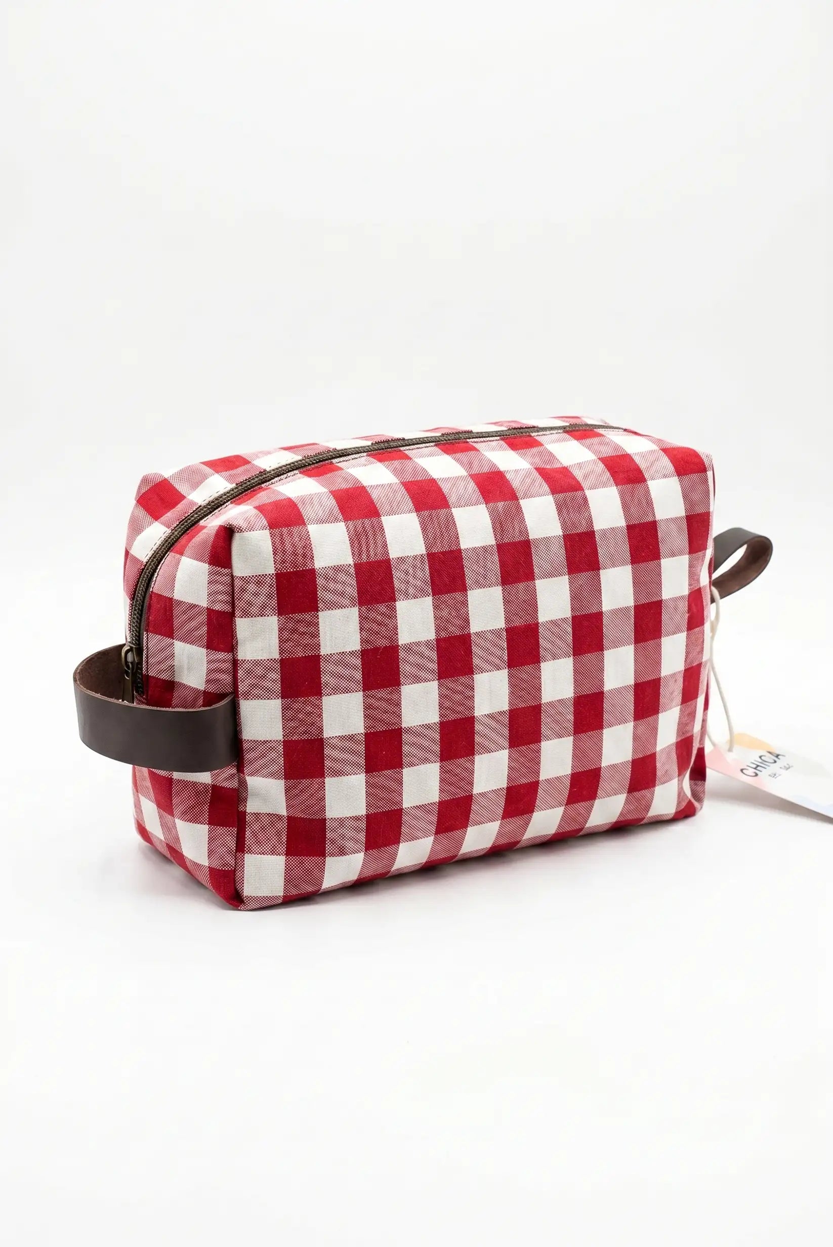 Neceser de verano con estampado de cuadros vichy rojo y blanco, asa marrón y cremallera.