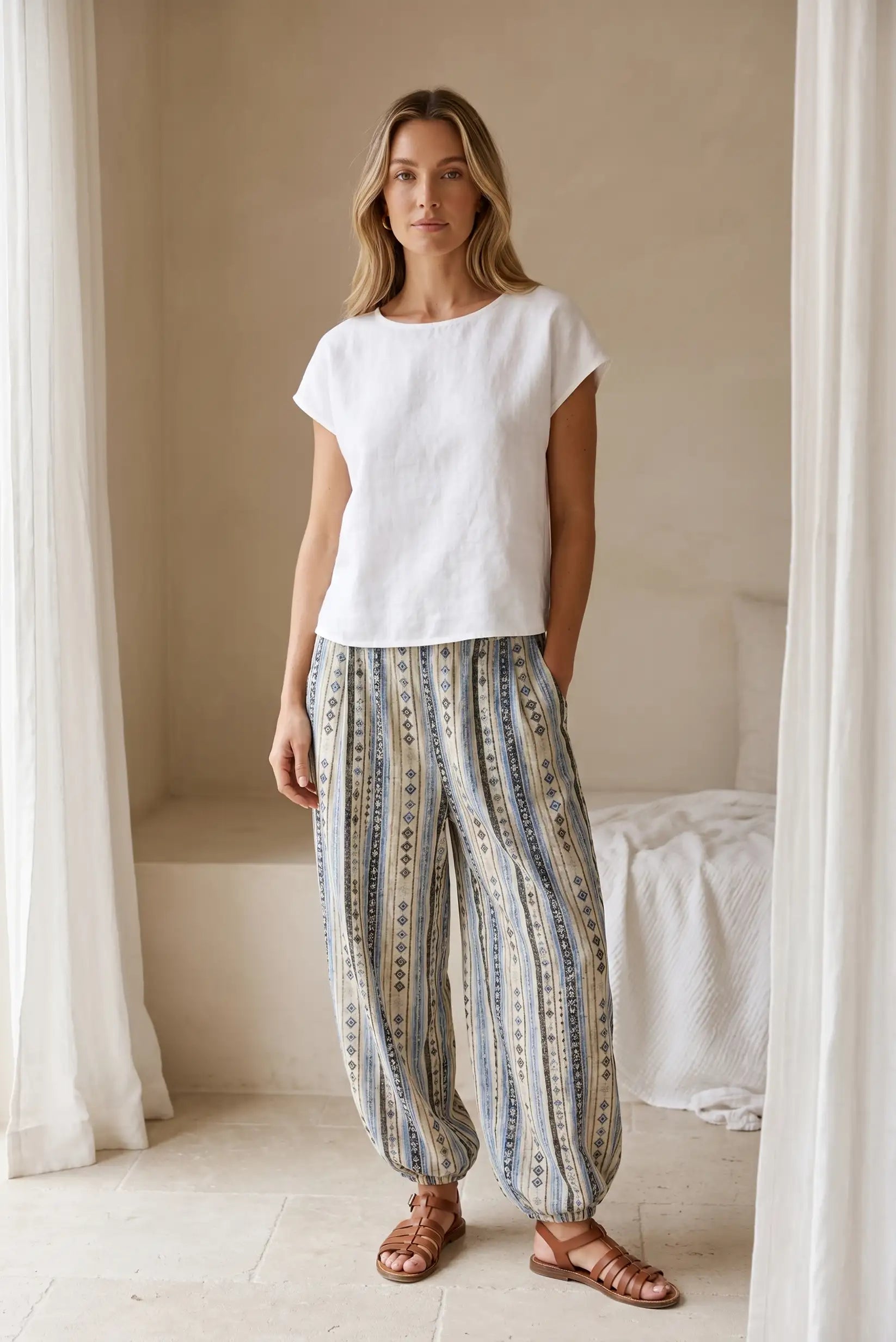 Mujer con pantalón bombacho largo azul étnico y blusa blanca casual en ambiente minimalista