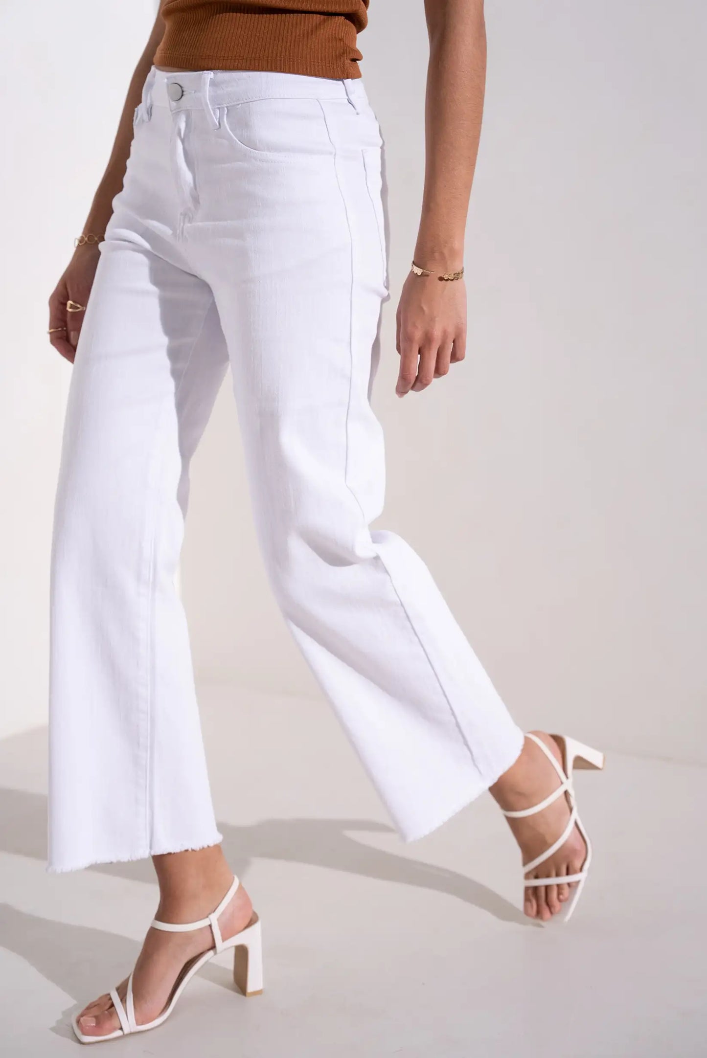 Pantalón blanco de mujer flare primaveral, combinado con sandalias de tacón blancas.