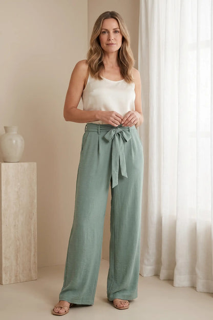 Pantalones anchos verdes con cinturón, top blanco y sandalias, look casual y cómodo para mujer
