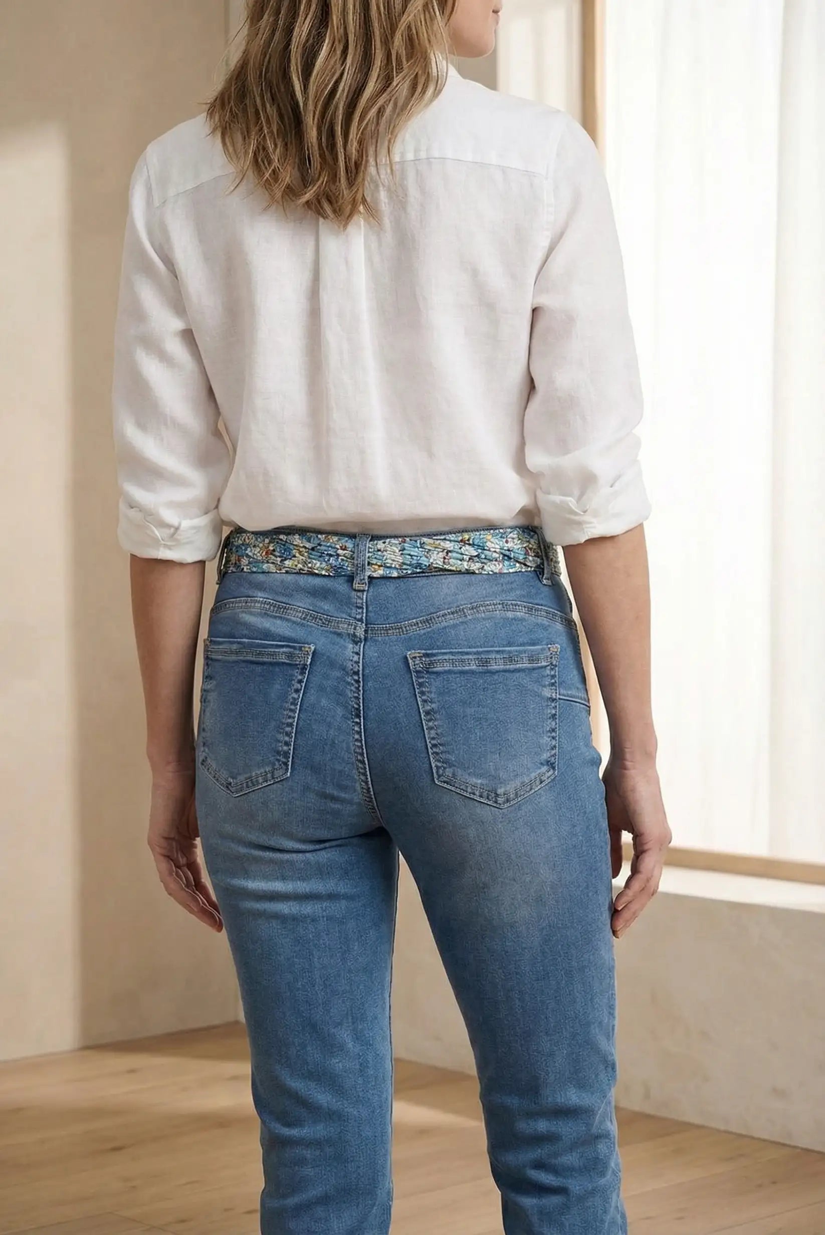 Pantalón vaquero azul de mujer con cinturón estampado y camisa blanca, moda casual