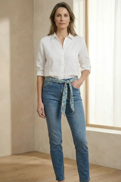 Mujer con camisa blanca y pantalón vaquero azul, cinturón de tela estampada, moda casual primavera