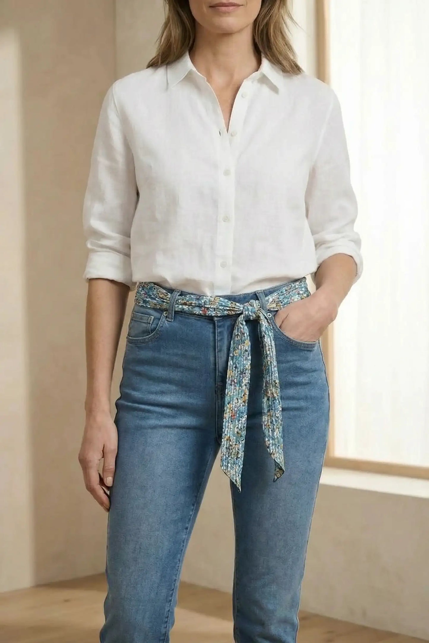 Mujer con pantalón vaquero azul y cinturón de tela estampado, camisa blanca de manga larga