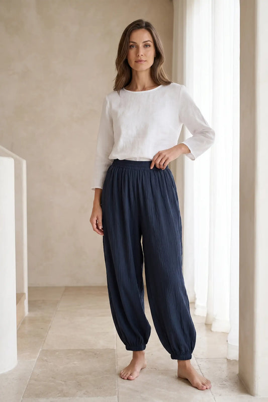 Mujer con pantalón bombacho azul marino y blusa blanca en ambiente minimalista