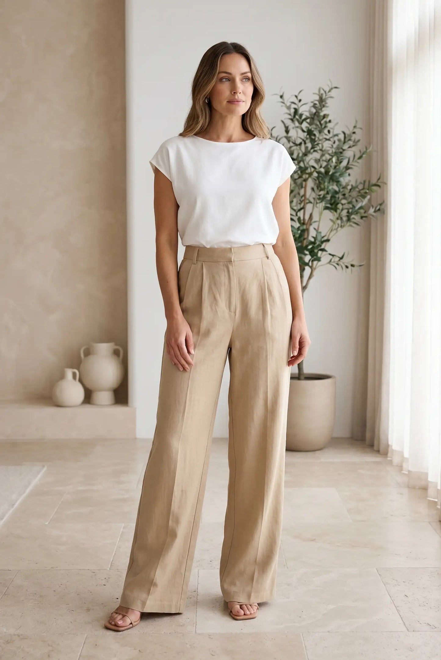 Mujer con pantalón largo fluido beige y blusa blanca, estilo casual y elegante