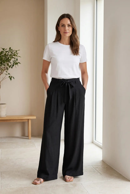 Mujer con pantalón fluido negro largo y camiseta blanca en ambiente moderno y luminoso