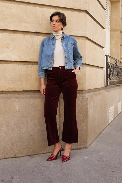 Mujer con pantalón largo de micropana burdeos, chaqueta denim y tacones en calle urbana