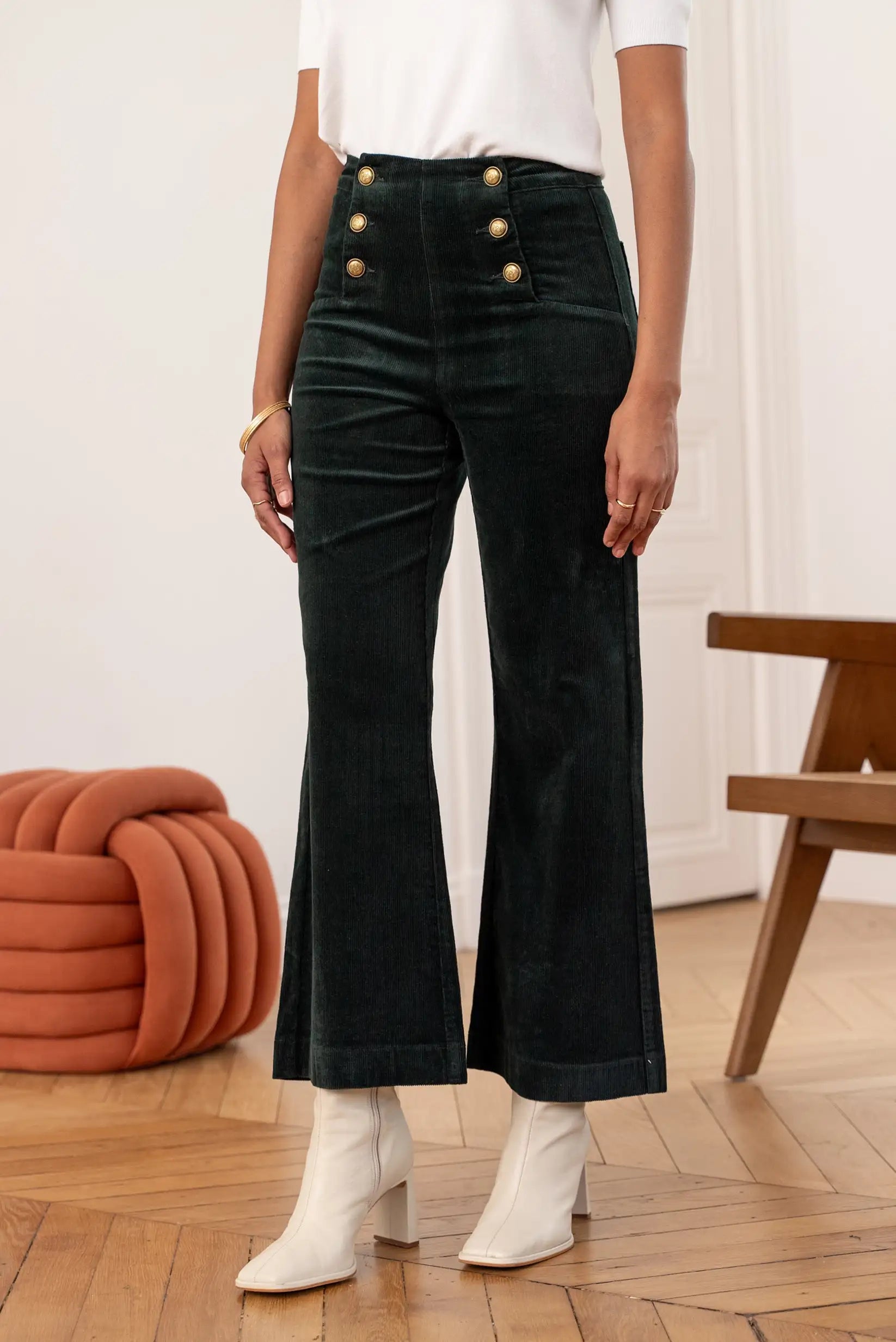 Pantalón largo micropana verde botella con botones dorados, estilo acampanado y botas blancas