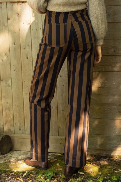 Pantalones de rayas verticales marrón y negro con corte recto y zapato marrón.