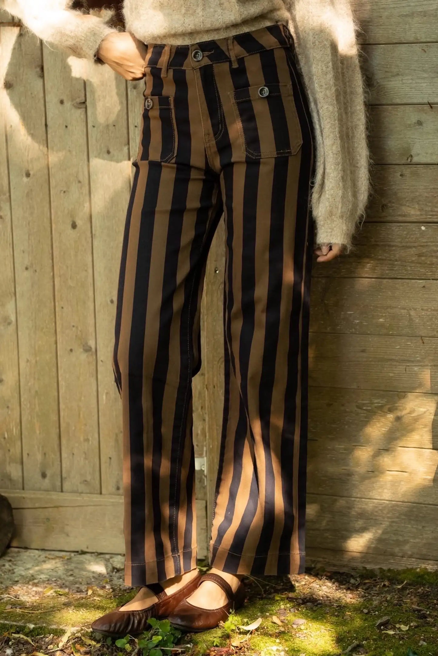 Mujer vistiendo pantalones de rayas verticales marrones y negras con zapatos Mary Jane marrón