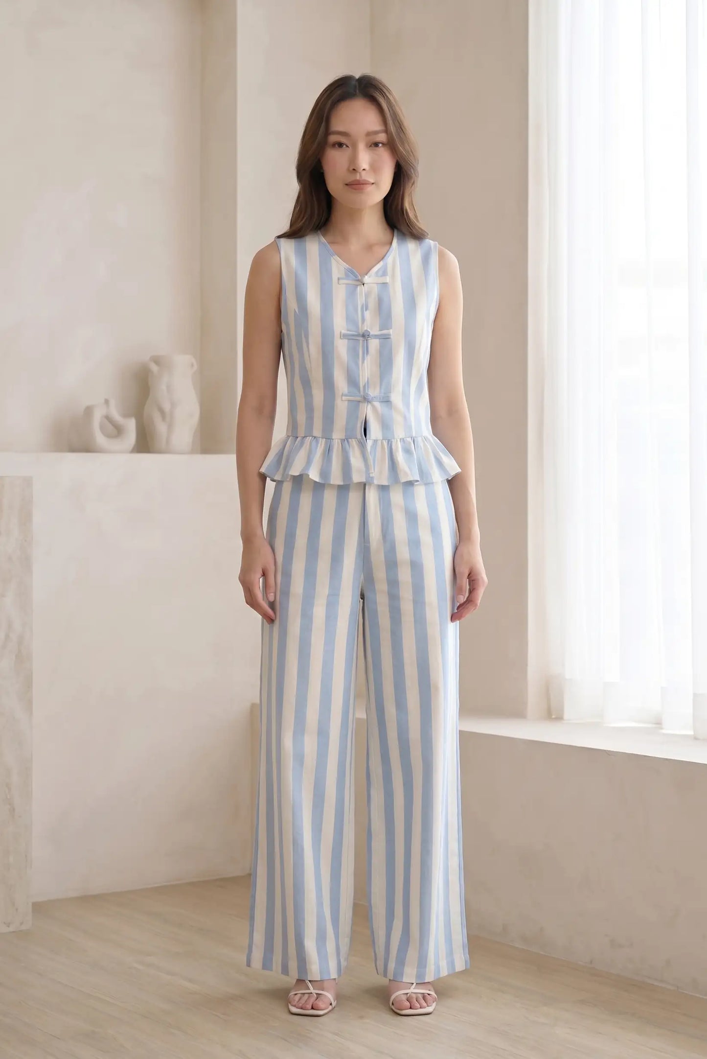 Mujer con conjunto de tirantes y pantalón largo de rayas azul y blanco en interior luminoso