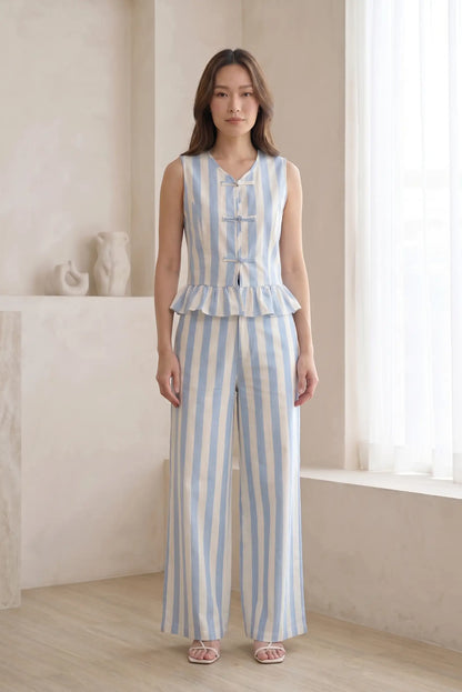 Mujer con conjunto de tirantes y pantalón largo de rayas azul y blanco en interior luminoso