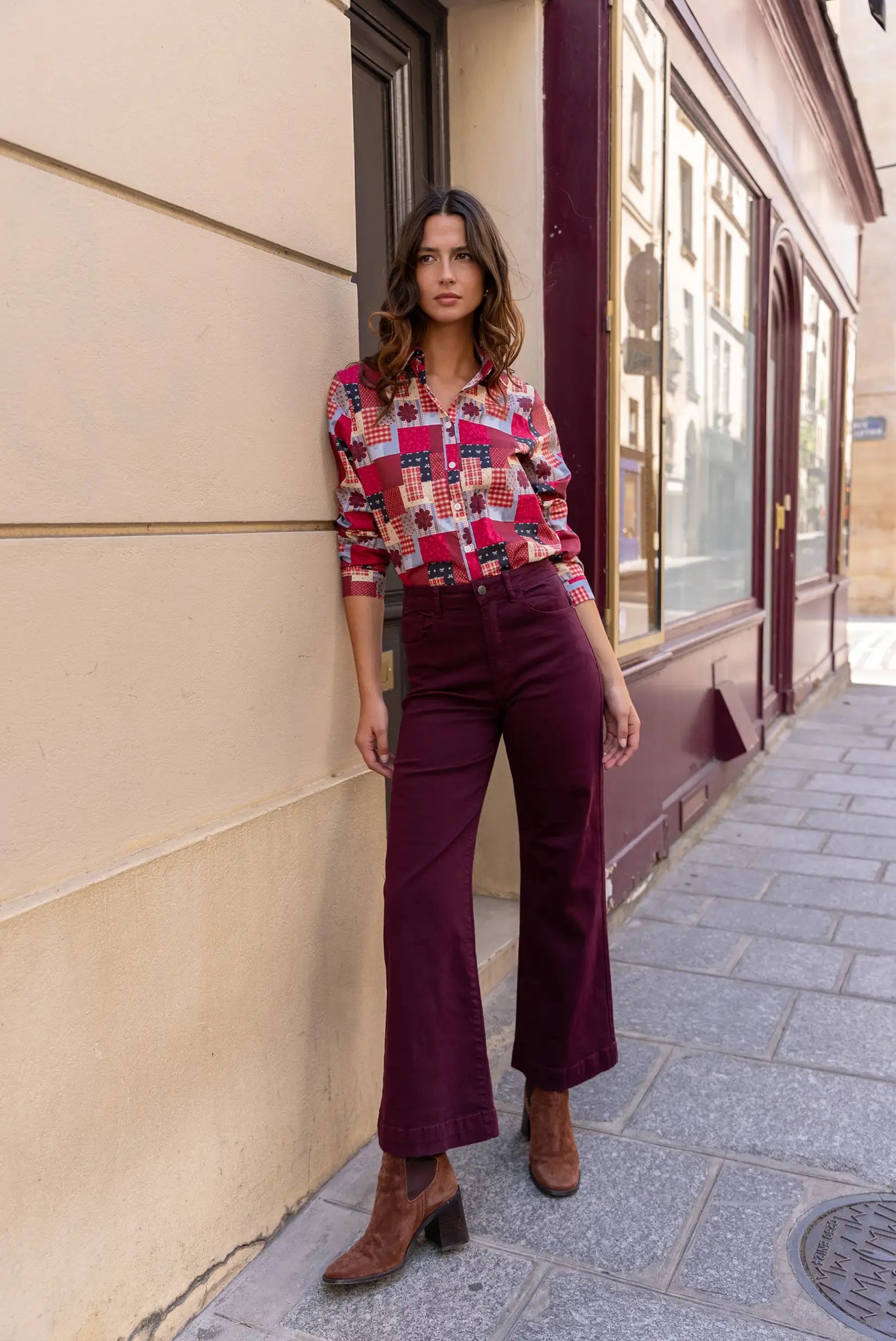 Mujer con camisa estampada patchwork y pantalones anchos burdeos, estilo urbano y moderno
