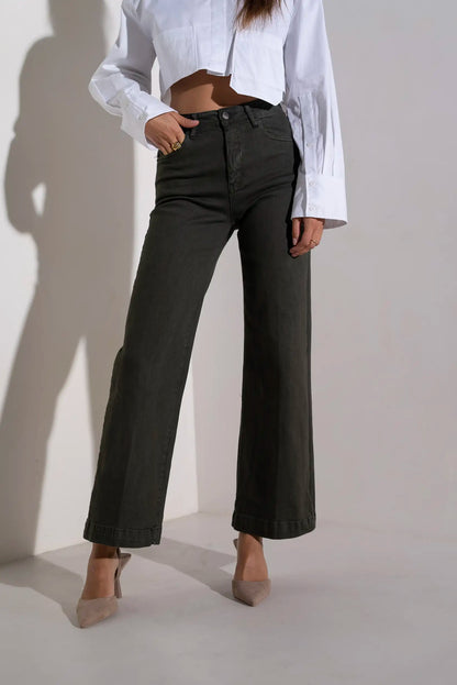 Pantalones vaqueros anchos de talle alto en color verde oscuro, combinados con blusa blanca y tacones