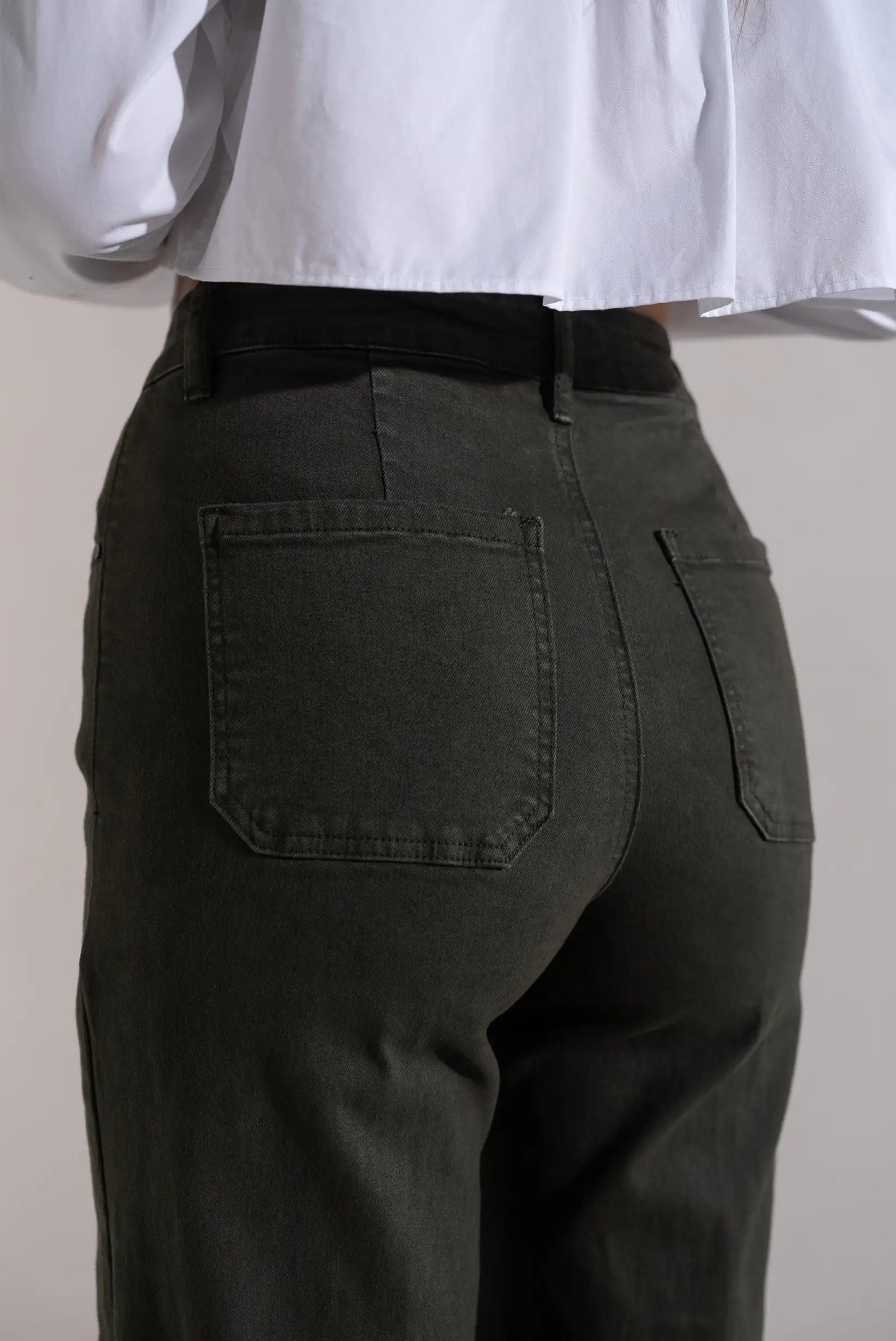 Pantalones vaqueros verdes de corte recto con bolsillos traseros, combinados con blusa blanca