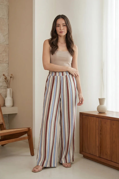 Mujer usando pantalón fluido largo de rayas azul y marrón, look casual femenino