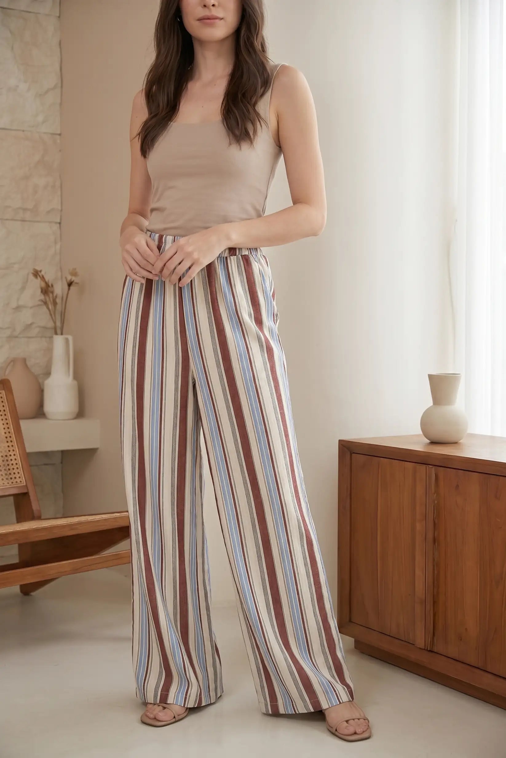 Pantalón largo fluido de mujer con rayas azul, beige y marrón en ambiente casual
