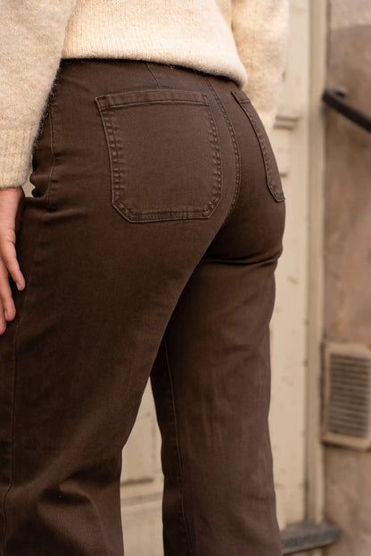 Pantalones marrones de mujer con bolsillos traseros, combinados con jersey beige, ideal para moda femenina casual