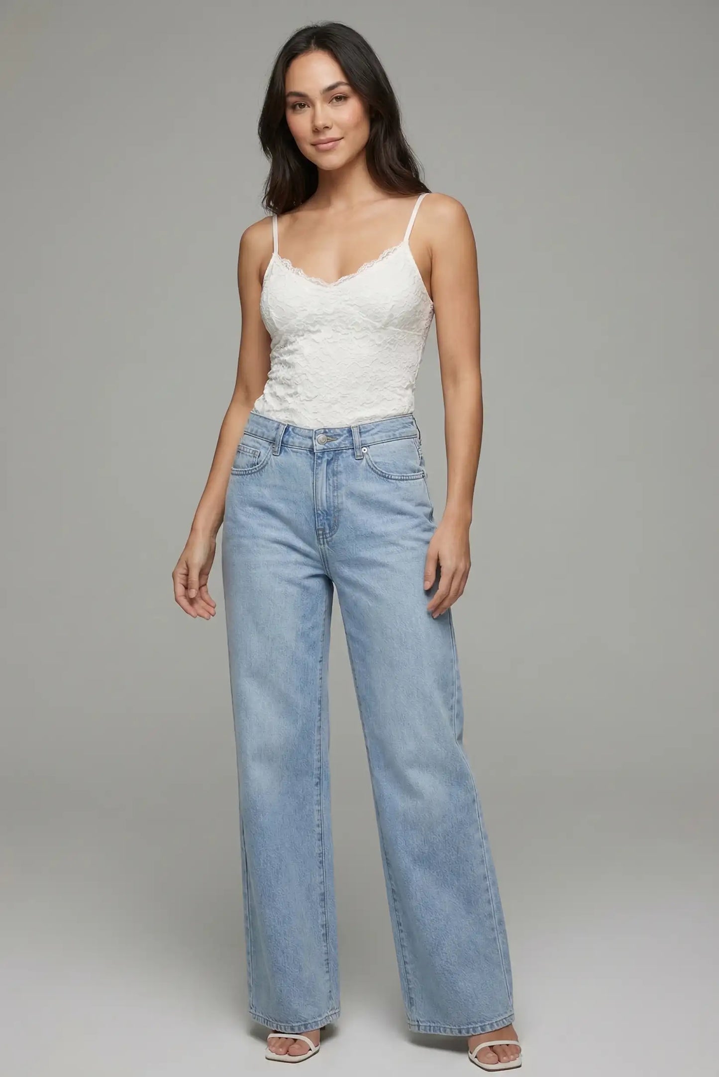 Mujer con pantalón vaquero azul de pierna ancha y top blanco de tirantes, moda casual femenina.