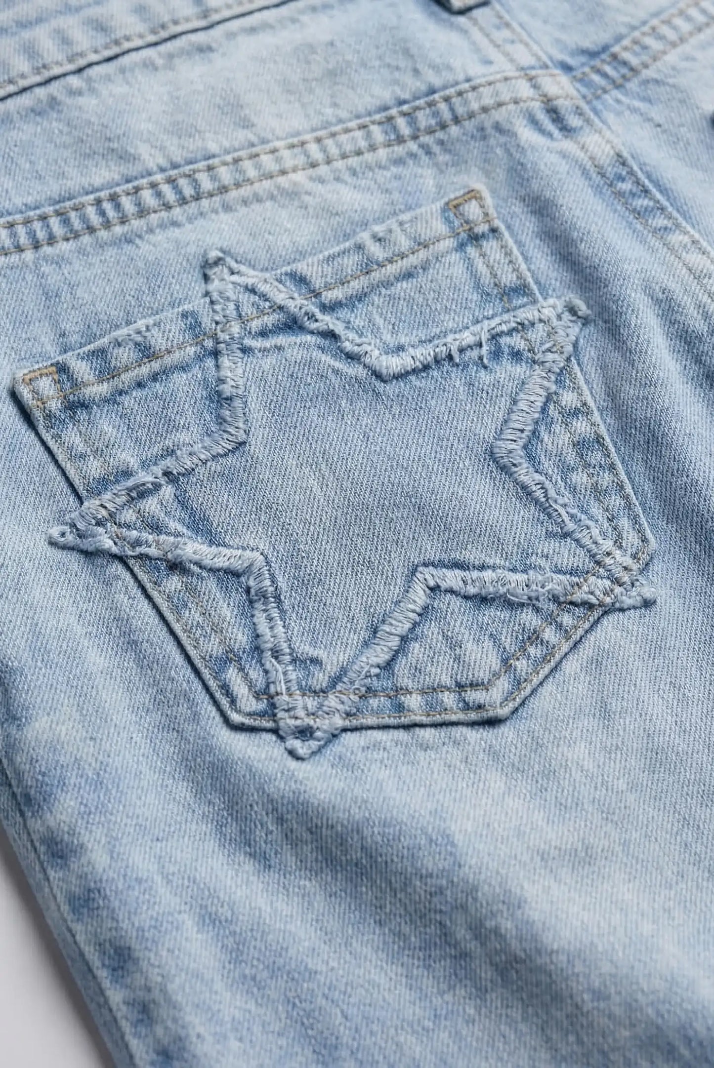Detalle de bolsillo trasero con estrella en pantalón vaquero azul claro de mujer