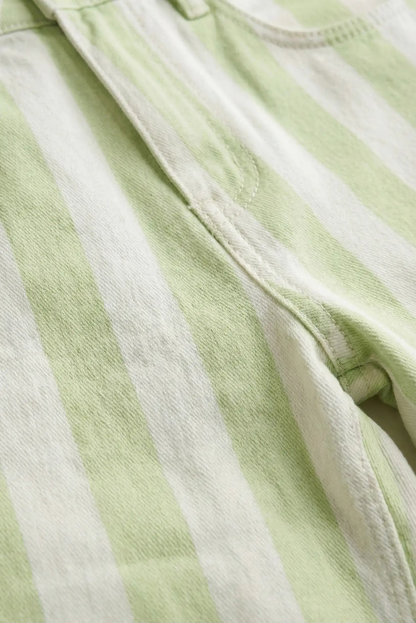 Detalle de pantalón mujer vaquero con rayas blancas y verde menta, tejido denim.