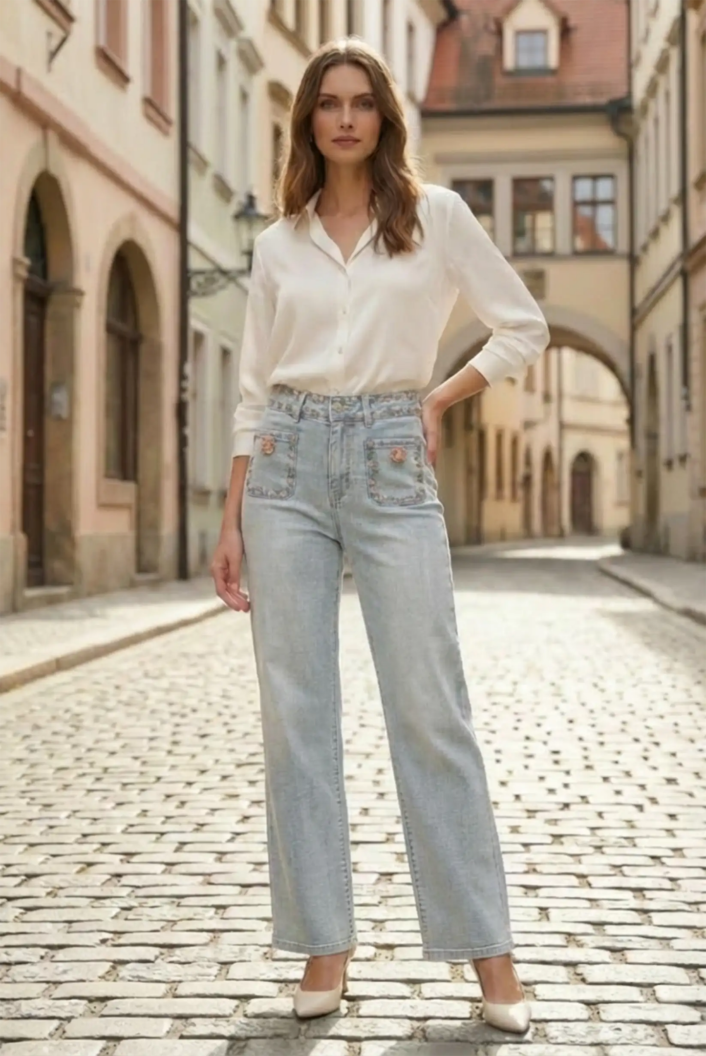 Mujer con pantalón vaquero azul claro floral de primavera y blusa blanca en calle adoquinada, moda femenina CHICA del Sur
