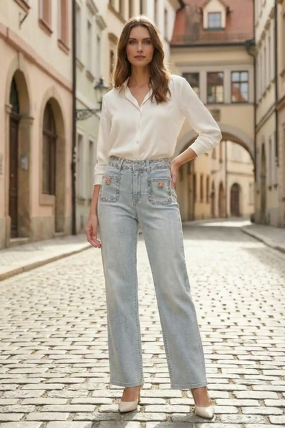 Mujer con pantalón vaquero azul claro floral de primavera y blusa blanca en calle adoquinada, moda femenina CHICA del Sur