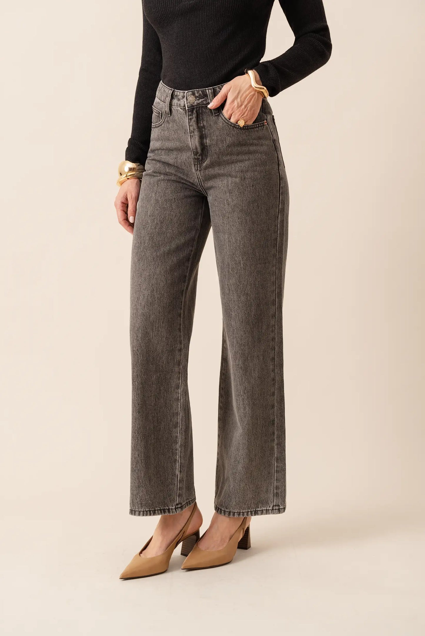 Jeans pitillo gris oscuro con corte recto, combinados con top negro y zapatos de tacón beige. Moda femenina elegante y cómoda.