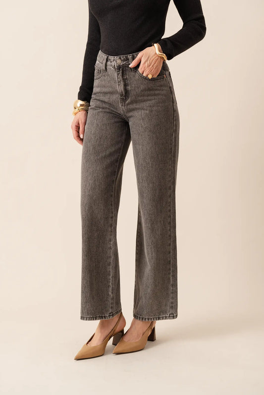 Jeans pitillo gris oscuro con corte recto, combinados con top negro y zapatos de tacón beige. Moda femenina elegante y cómoda.