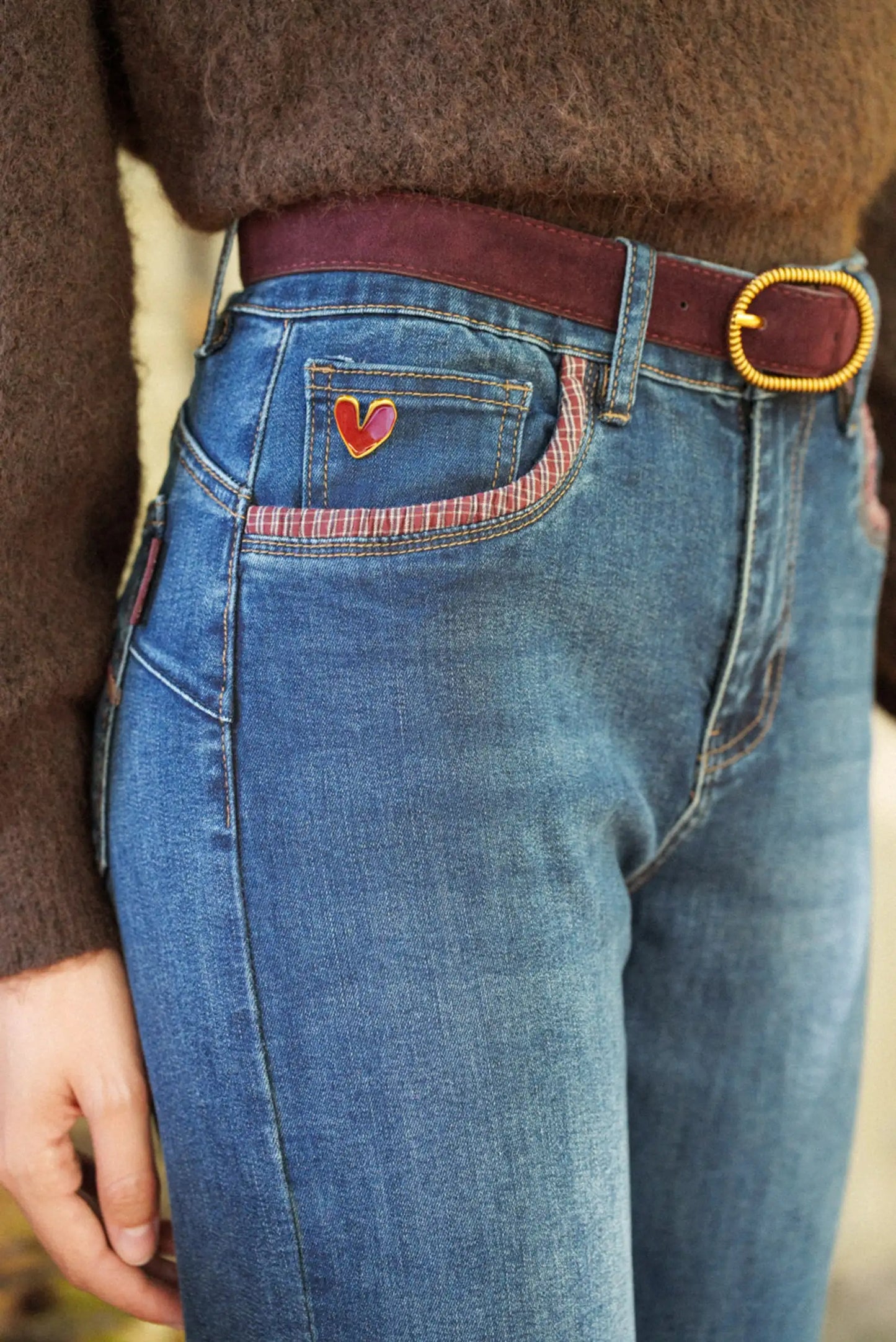 Vaqueros azules con bolsillo decorado con corazón rojo y cinturón marrón, moda femenina