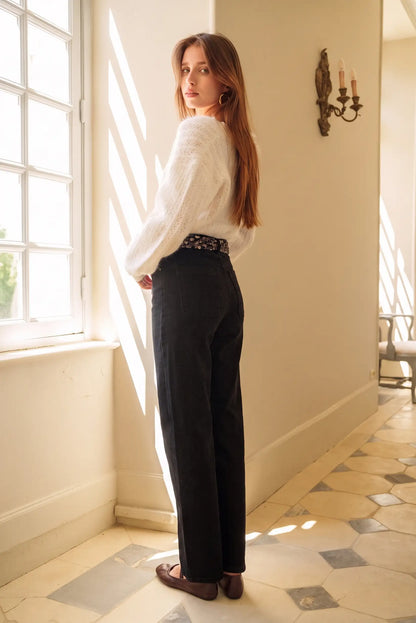 Mujer con jersey blanco de punto y pantalones negros anchos, estilo casual elegante para mujer