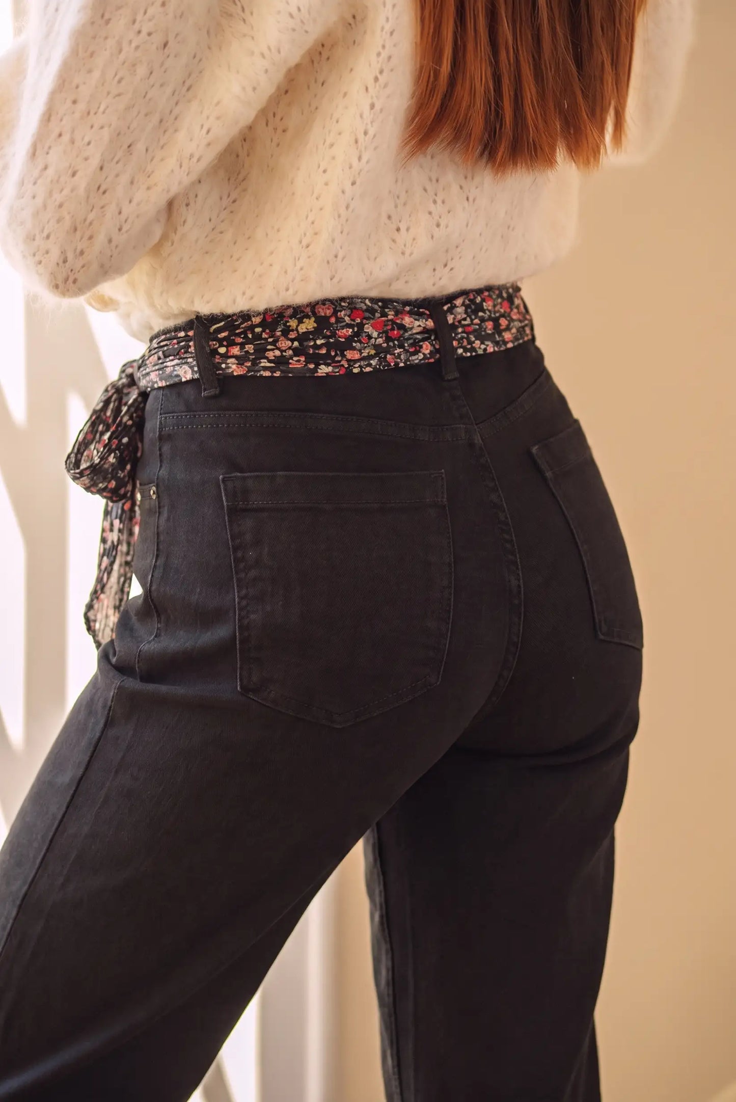 Jeans negros con cinturón floral y suéter blanco, moda femenina cómoda y estilizada