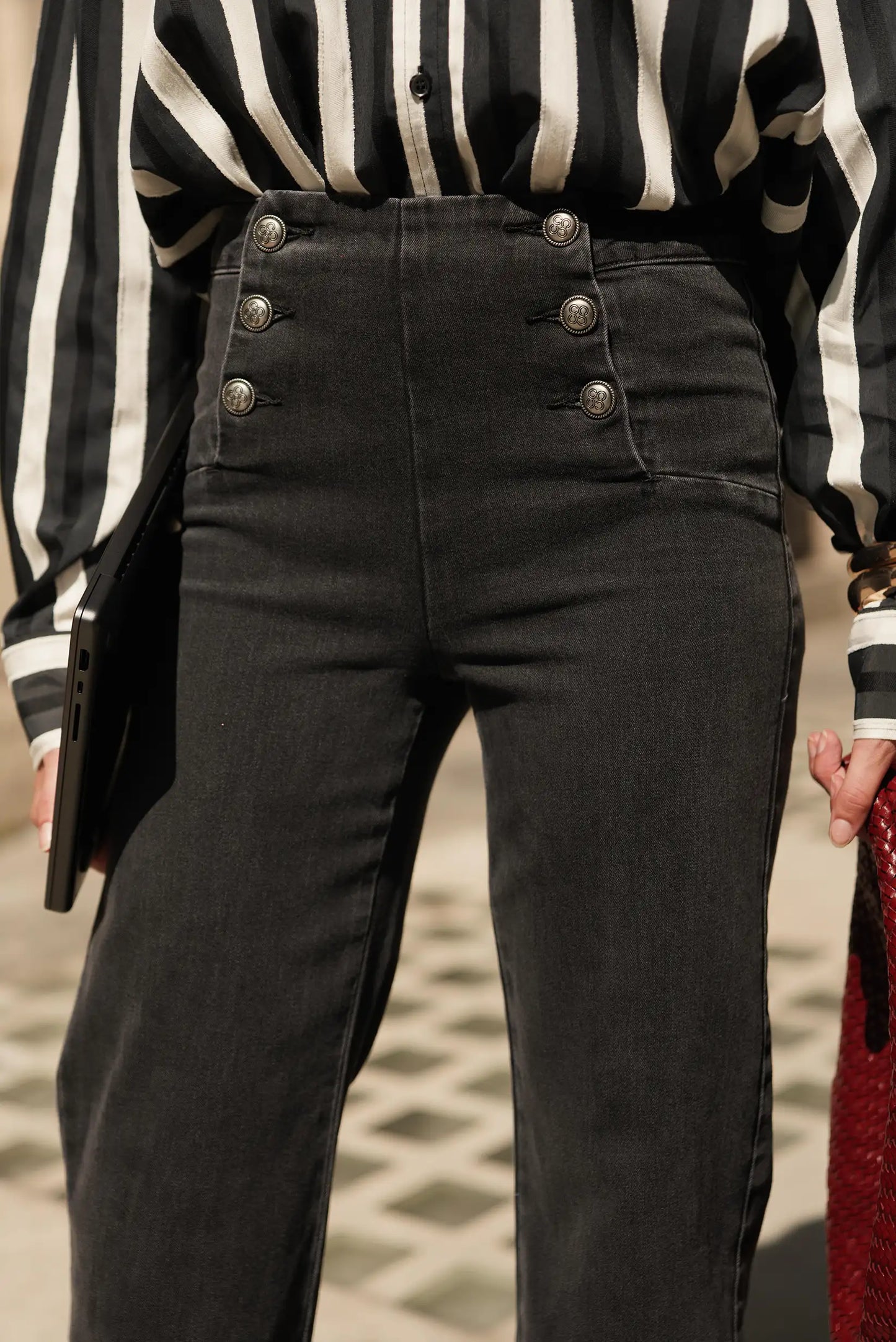 Pantalón vaquero negro con botones decorativos y camisa a rayas, moda femenina elegante y urbana