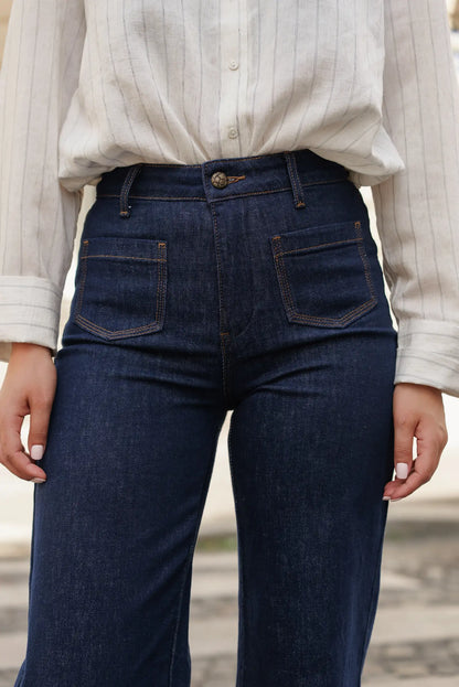 Vaqueros azul oscuro con corte recto y costuras en contraste, combinados con blusa de rayas finas. Moda femenina cómoda y versátil.