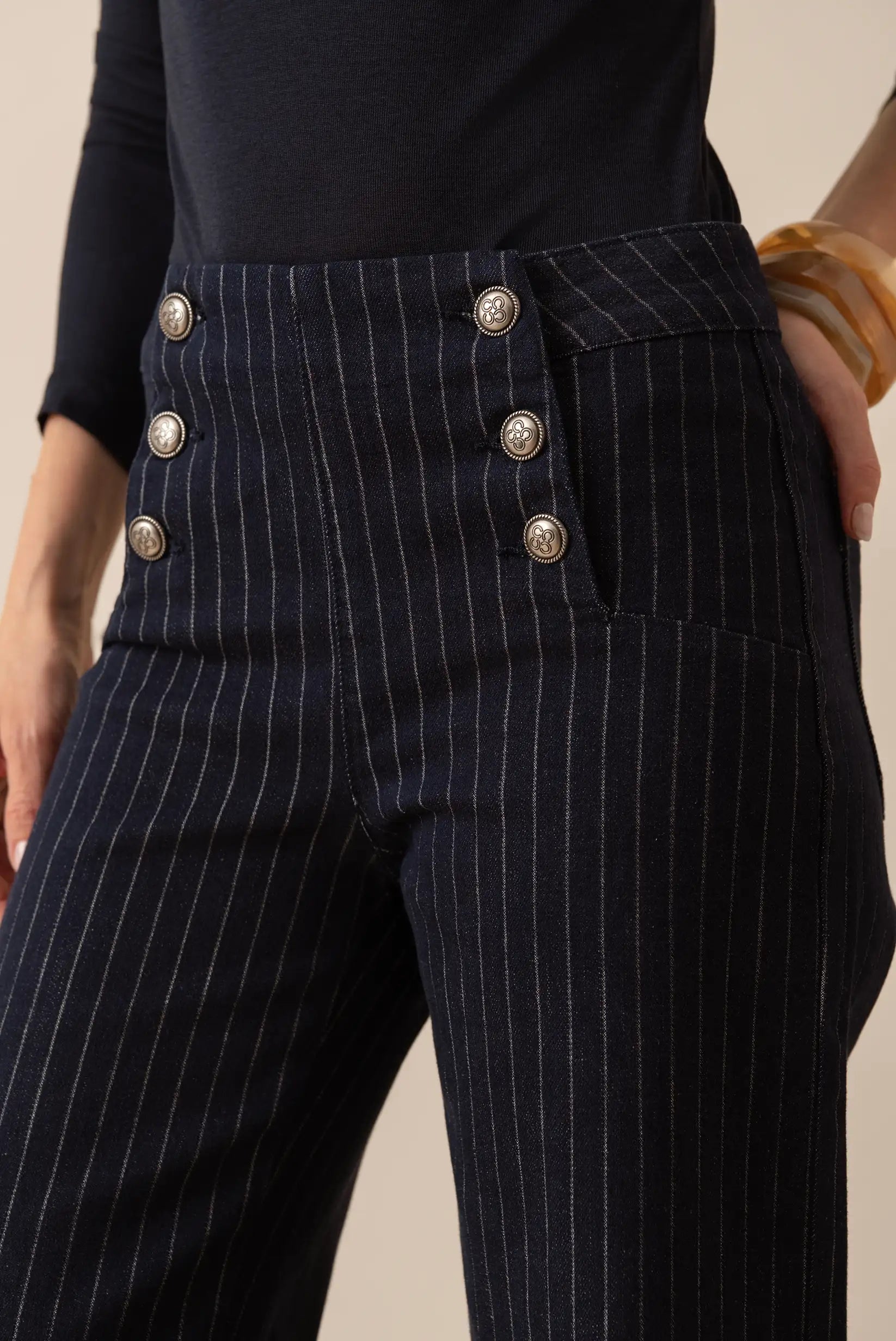 Pantalón de vestir a rayas finas con botones decorativos en cintura alta, ideal para look elegante y sofisticado.