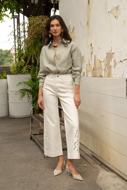 Mujer con camisa beige y pantalón largo blanco calado, look casual de moda femenina.