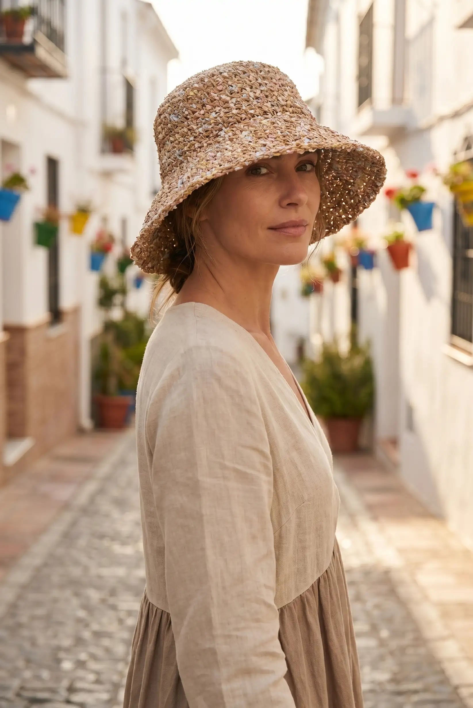 Mujer con sombrero de paja y vestido casual en calle blanca con flores, moda femenina verano