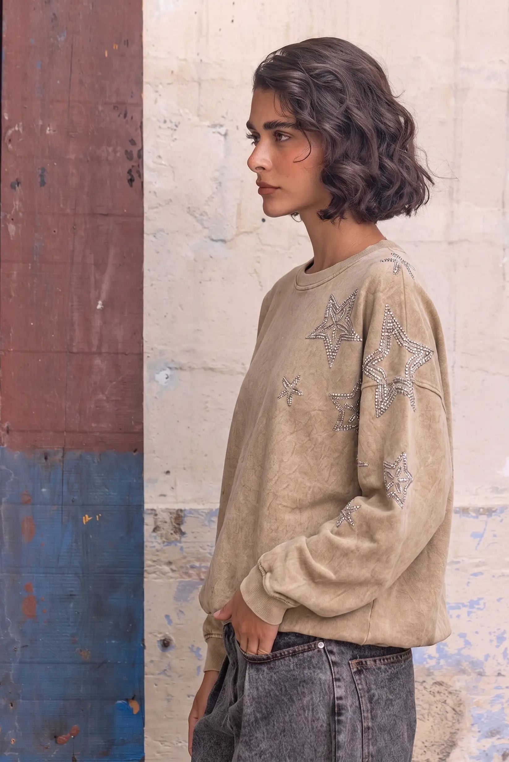 Mujer de perfil con sudadera beige lavada decorada con estrellas de brillantes