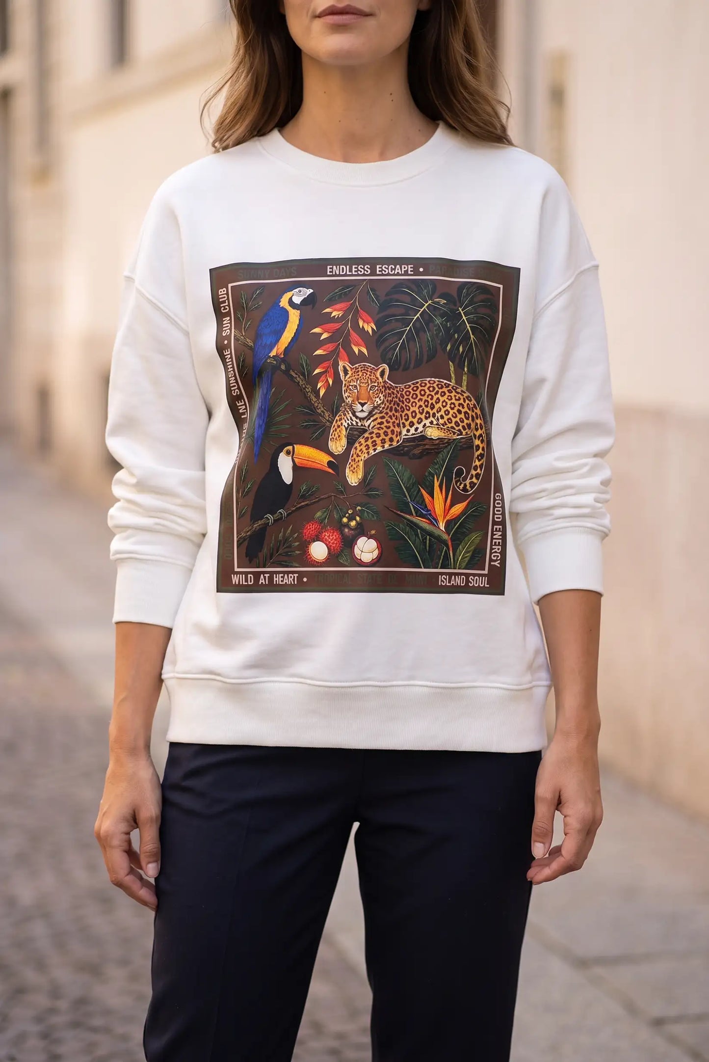Mujer vistiendo sudadera blanca con estampado tropical de jaguar y tucán