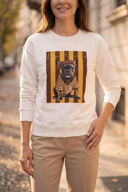 Mujer vistiendo sudadera blanca con estampado de bulldog francés sobre rayas amarillas.