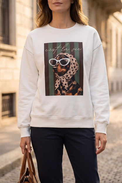 Mujer vistiendo sudadera blanca con estampado de perro con gafas de sol y pañuelo.