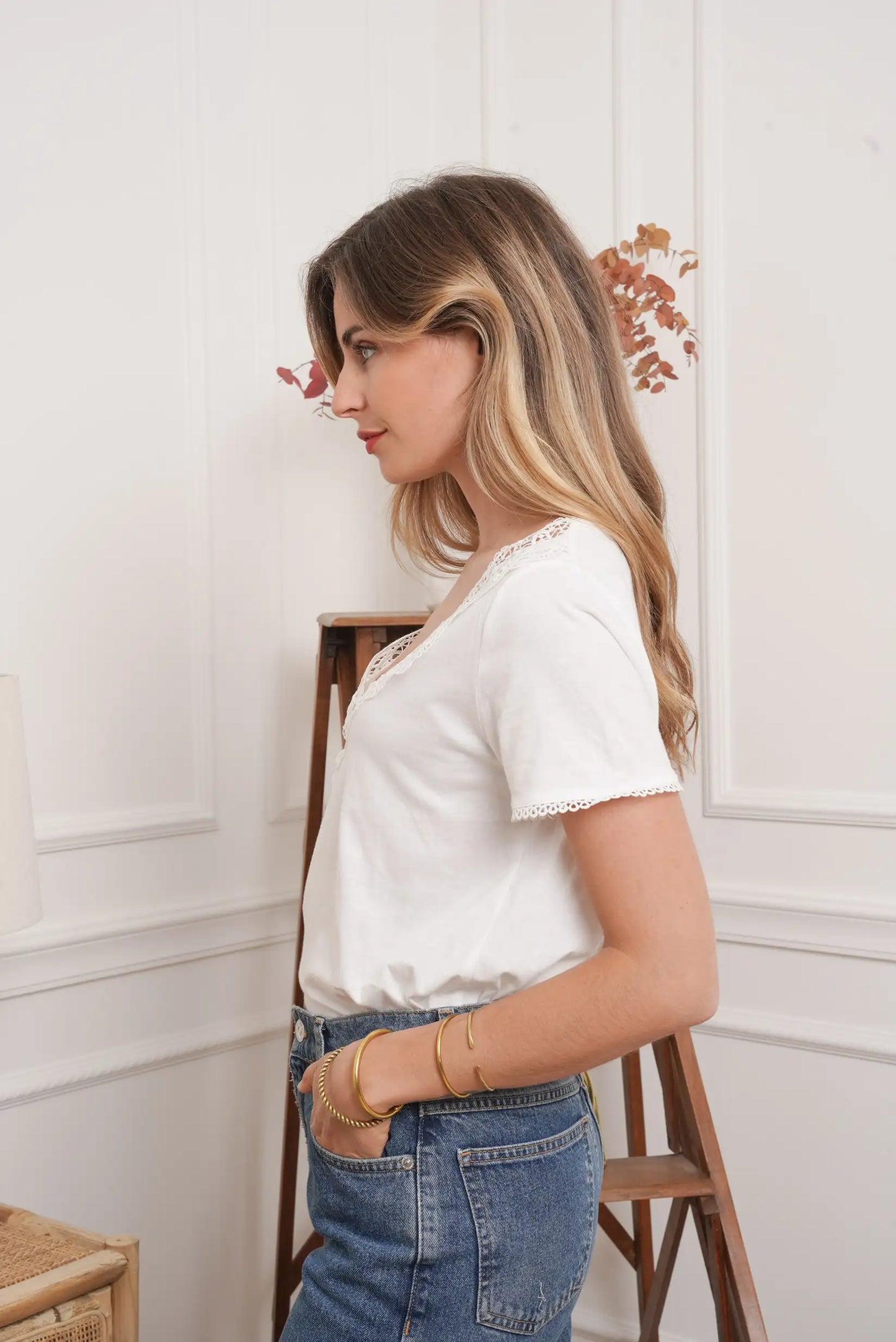 Mujer con top blanco de manga corta y encaje, combinando con jeans azules en estilo casual